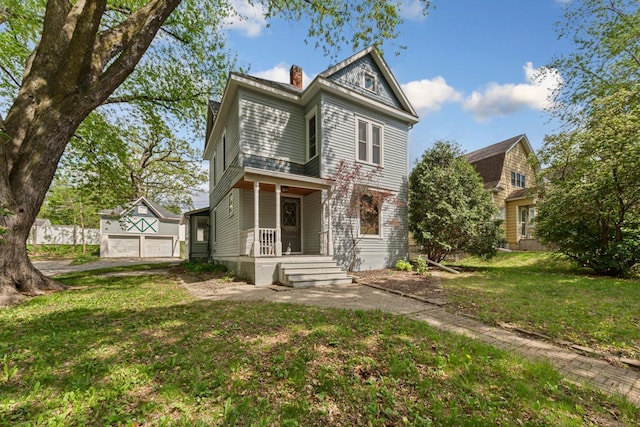view of front of home featuring a porch, a chimney, a front lawn, and a detached garage