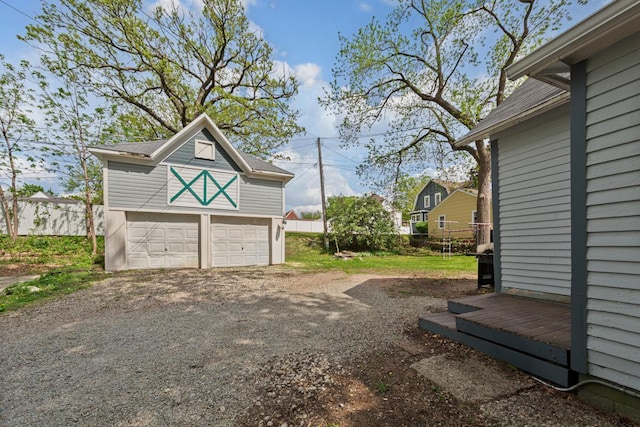 view of yard with an outdoor structure, a detached garage, and fence