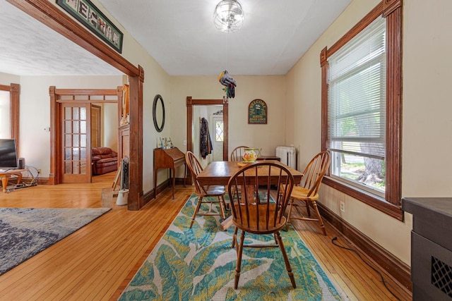 dining area with hardwood / wood-style floors, baseboards, french doors, and radiator