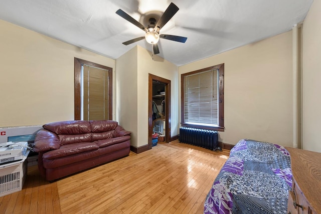 bedroom featuring radiator, light wood-style floors, ceiling fan, and a closet