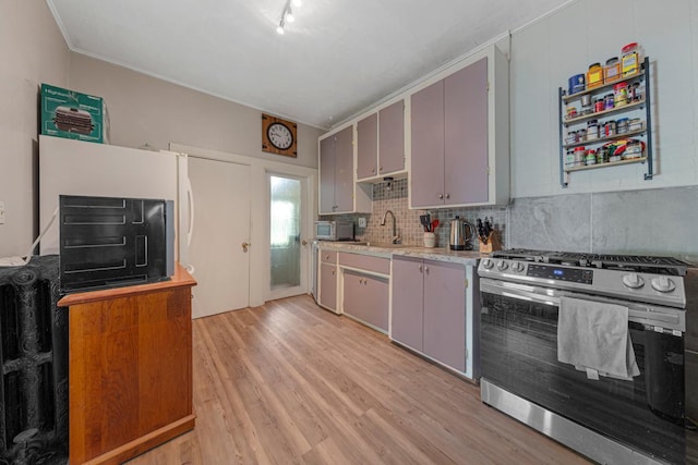 kitchen featuring appliances with stainless steel finishes, light wood finished floors, a sink, and light countertops