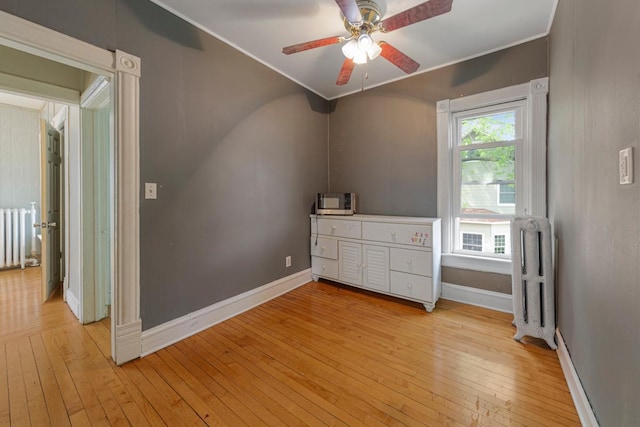 unfurnished room with radiator heating unit, ornamental molding, light wood-type flooring, and baseboards