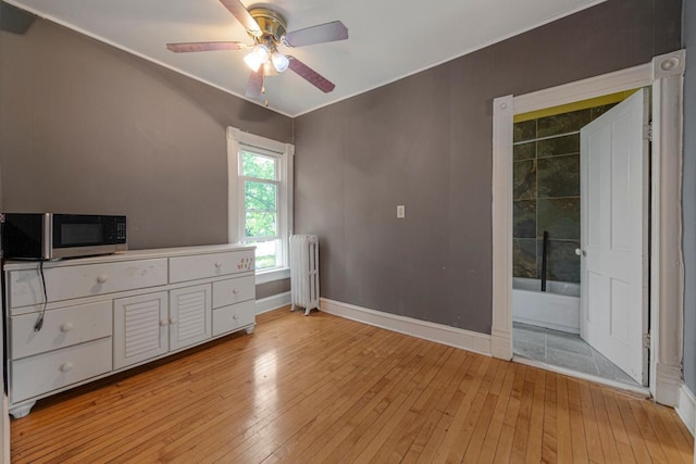 bedroom featuring radiator heating unit, light wood-style floors, baseboards, ornamental molding, and a ceiling fan