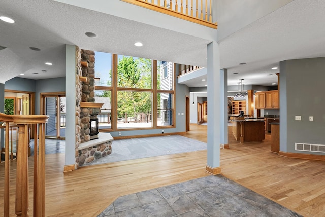 entryway featuring light wood finished floors, baseboards, a textured ceiling, recessed lighting, and a fireplace