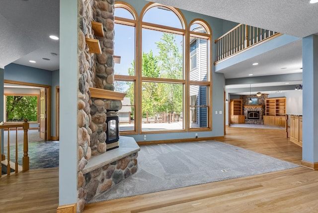 living room with a fireplace, baseboards, wood finished floors, a wood stove, and a textured ceiling