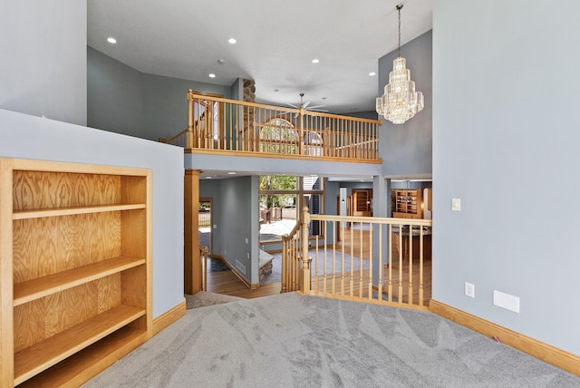 living room featuring ceiling fan, baseboards, recessed lighting, a chandelier, and a high ceiling