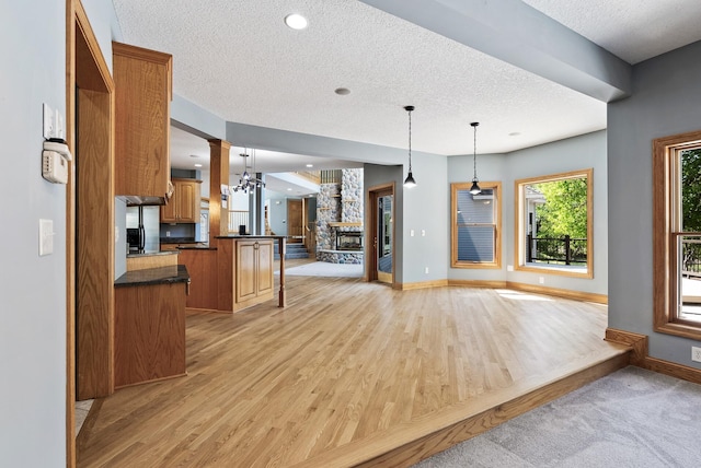 kitchen featuring open floor plan, dark countertops, a textured ceiling, ornate columns, and light wood-style floors
