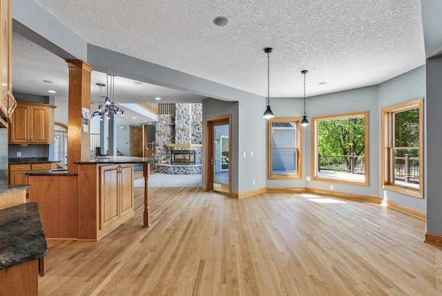 kitchen featuring a textured ceiling, open floor plan, light wood-style floors, and baseboards