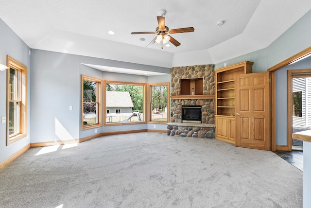 unfurnished living room with carpet flooring, ceiling fan, a fireplace, baseboards, and healthy amount of natural light