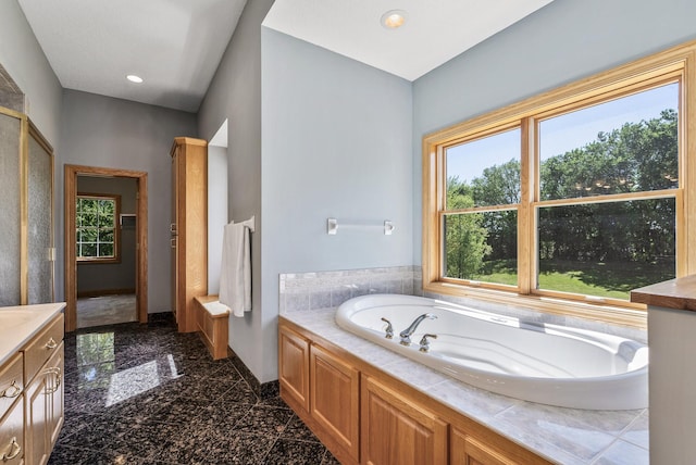 bathroom featuring granite floors, healthy amount of natural light, a bath, baseboards, and recessed lighting