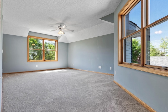 carpeted empty room featuring ceiling fan, a textured ceiling, and baseboards
