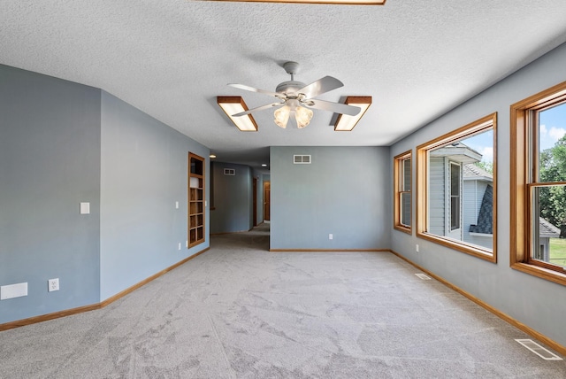 carpeted empty room featuring baseboards, a ceiling fan, and a textured ceiling