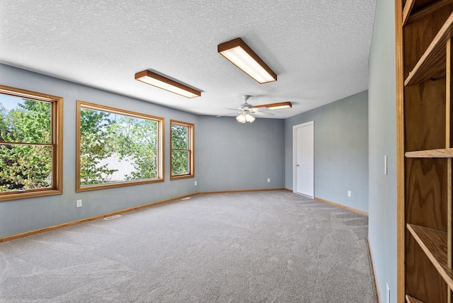 carpeted spare room with a ceiling fan, a textured ceiling, and baseboards