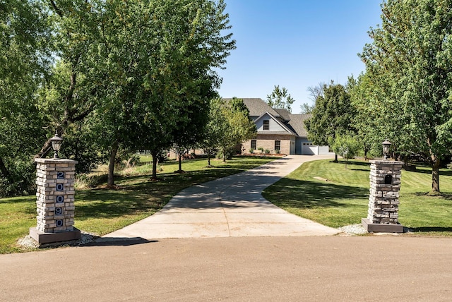 view of property hidden behind natural elements with a front yard and concrete driveway