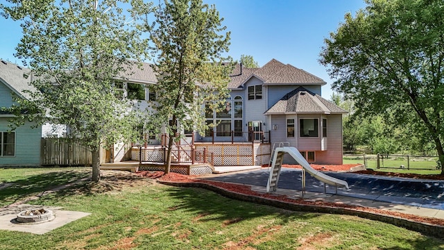 back of property featuring a wooden deck, a patio area, a fire pit, and a shingled roof