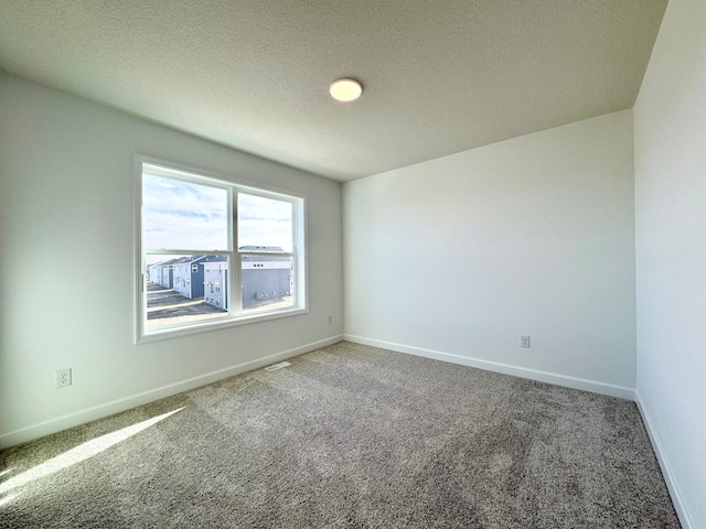 carpeted spare room featuring baseboards and a textured ceiling