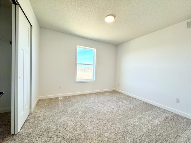 unfurnished bedroom with carpet floors, baseboards, a closet, and a textured ceiling