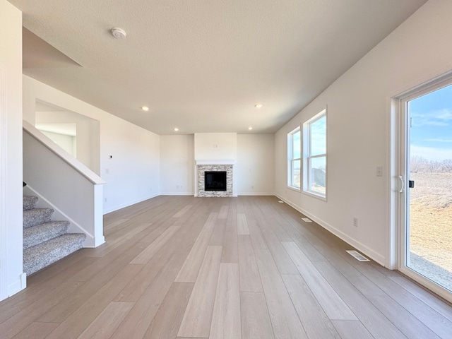 11367 84th St NE, Otsego, MN 55330 - unfurnished living room with wood finished floors, baseboards, stairs, a stone fireplace, and recessed lighting
