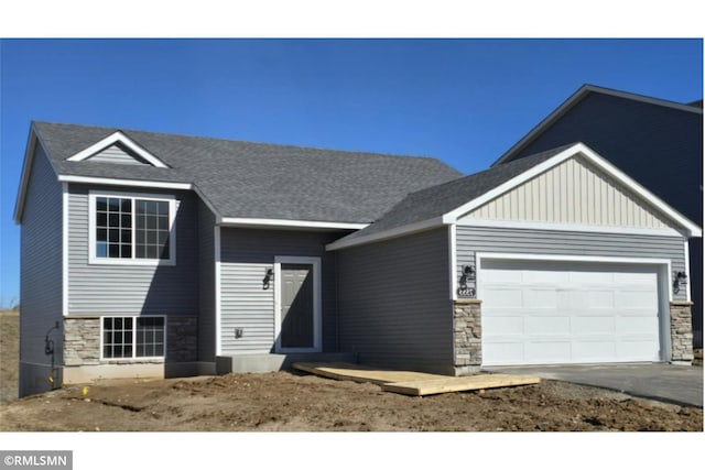 7497 147th Ln NW, Ramsey, MN 55303 - view of front of home with stone siding, a garage, driveway, and board and batten siding
