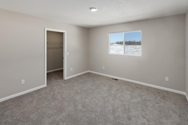 7497 147th Ln NW, Ramsey, MN 55303 - unfurnished bedroom with carpet floors, a spacious closet, baseboards, a textured ceiling, and a closet