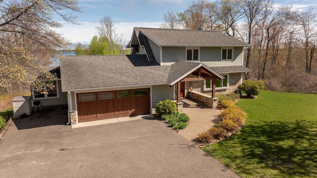 view of front of house with stone siding, driveway, a garage, a front yard, and roof with shingles