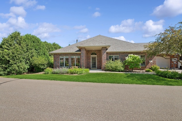 217 Canyon Dr, Hudson, WI 54016 - view of front facade featuring brick siding, a shingled roof, a front lawn, and a garage
