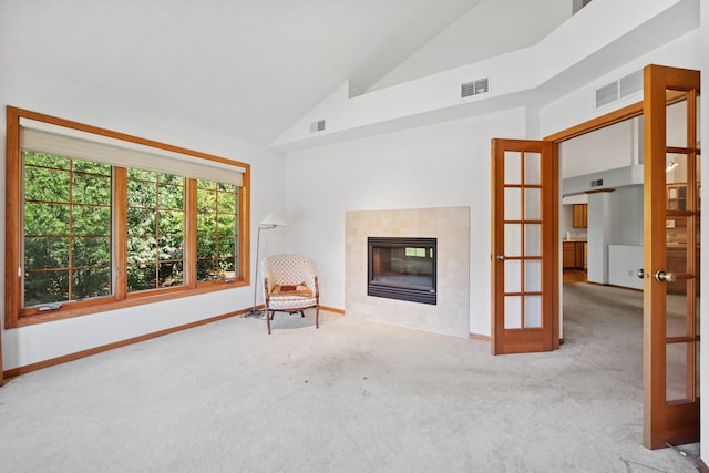 217 Canyon Dr, Hudson, WI 54016 - unfurnished living room featuring french doors, carpet flooring, high vaulted ceiling, and a tiled fireplace