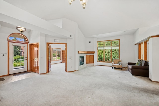 217 Canyon Dr, Hudson, WI 54016 - unfurnished living room with light carpet, healthy amount of natural light, high vaulted ceiling, a tile fireplace, and a chandelier