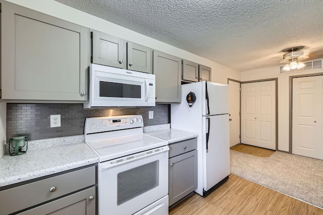 kitchen with white appliances, gray cabinetry, a textured ceiling, light wood-style flooring, and backsplash
