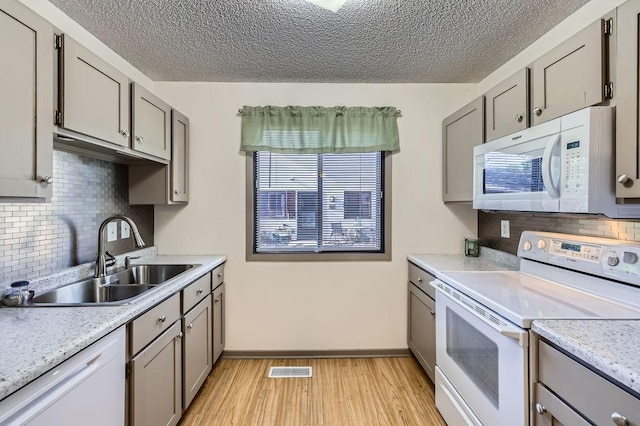 kitchen featuring white appliances, a sink, gray cabinetry, and a textured ceiling