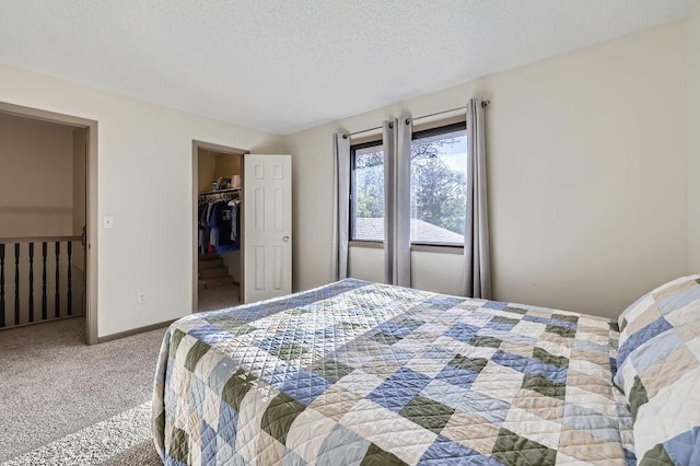 carpeted bedroom with a spacious closet, a textured ceiling, baseboards, and a closet