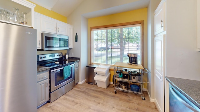 kitchen featuring stainless steel appliances, light wood finished floors, white cabinets, baseboards, and vaulted ceiling