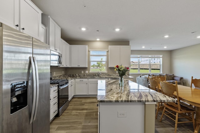 16386 Jaffna Pl, Lakeville, MN 55044 - kitchen with appliances with stainless steel finishes, wood finished floors, a center island, light stone countertops, and a sink