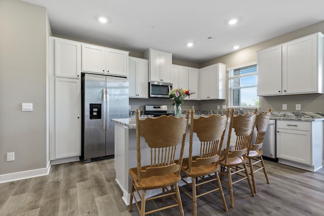 16386 Jaffna Pl, Lakeville, MN 55044 - kitchen with appliances with stainless steel finishes, wood finished floors, white cabinets, recessed lighting, and light stone counters