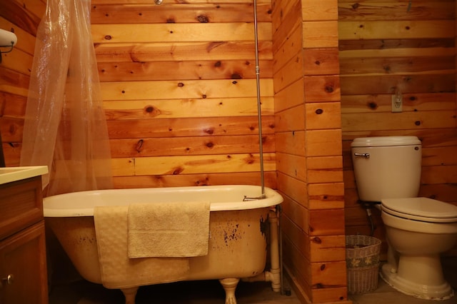 bathroom with wood walls, toilet, a tub to relax in, and vanity