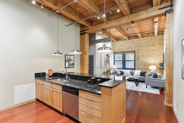kitchen with wooden ceiling with exposed beams, stainless steel dishwasher, a sink, rail lighting, and brick wall