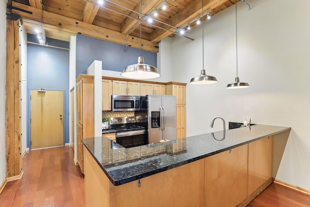 kitchen with appliances with stainless steel finishes, wood ceiling with exposed beams, a peninsula, wood finished floors, and backsplash