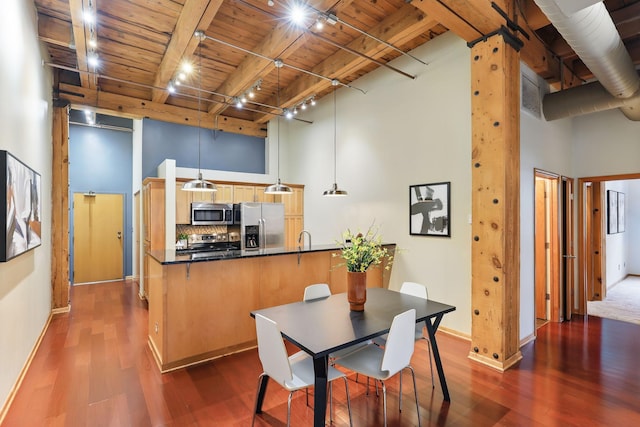 dining space with wood ceiling with exposed beams, dark wood-style floors, baseboards, track lighting, and a high ceiling