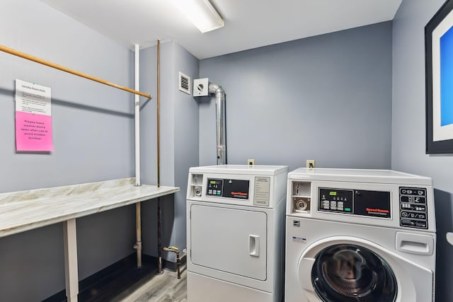 shared laundry with washing machine and dryer and wood finished floors