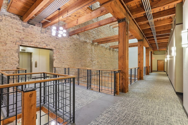 hall with wood ceiling with exposed beams, an upstairs landing, concrete floors, a chandelier, and a towering ceiling
