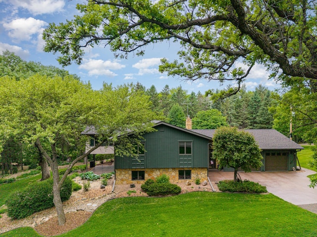tri-level home featuring concrete driveway, an attached garage, stone siding, and a chimney