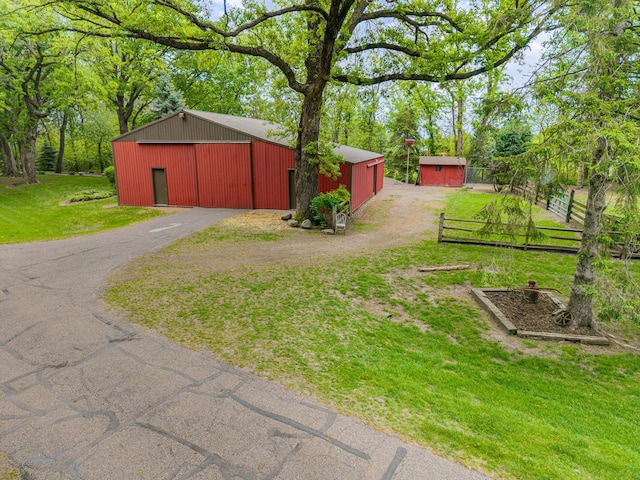 view of yard featuring a pole building, an outbuilding, a garage, and driveway