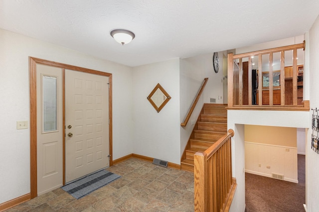entryway featuring stairway, baseboards, and stone finish floors