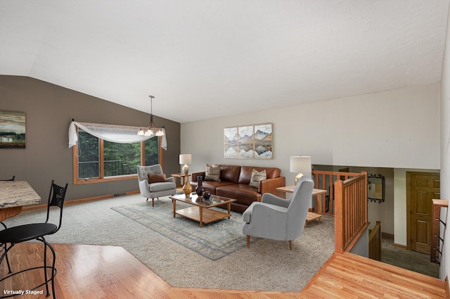 living room featuring lofted ceiling, wood finished floors, baseboards, and a chandelier