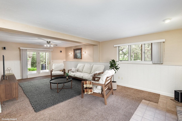 living room with a wainscoted wall, plenty of natural light, ceiling fan, and carpet floors