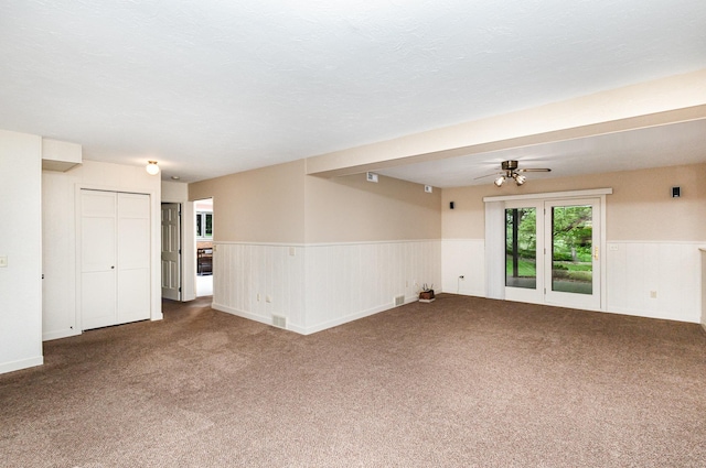 spare room featuring a wainscoted wall, carpet, and ceiling fan