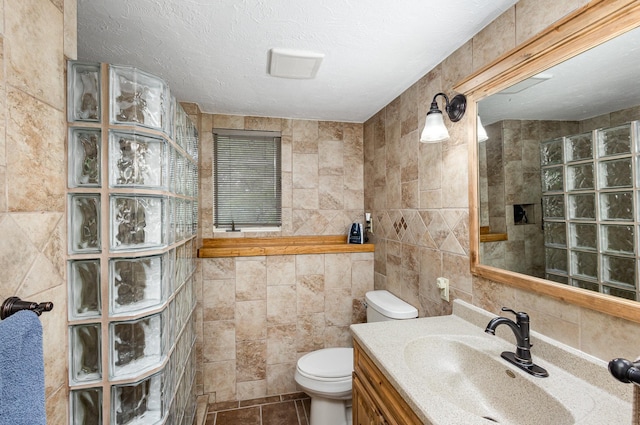 full bathroom with tile walls, a walk in shower, toilet, vanity, and tile patterned floors