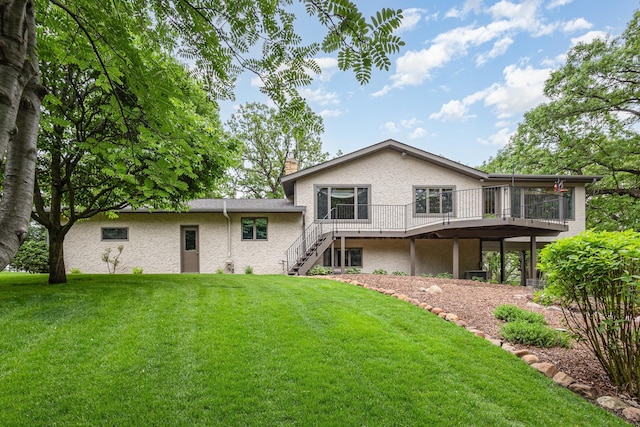 rear view of property featuring stairway, a chimney, a yard, a wooden deck, and a sunroom