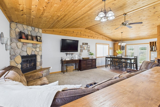 living room with a chandelier, vaulted ceiling, wooden ceiling, a stone fireplace, and baseboards