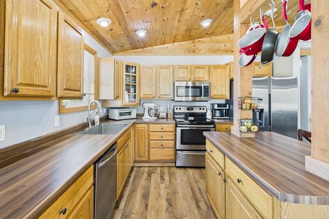kitchen with stainless steel appliances, wood counters, a sink, lofted ceiling, and light wood finished floors